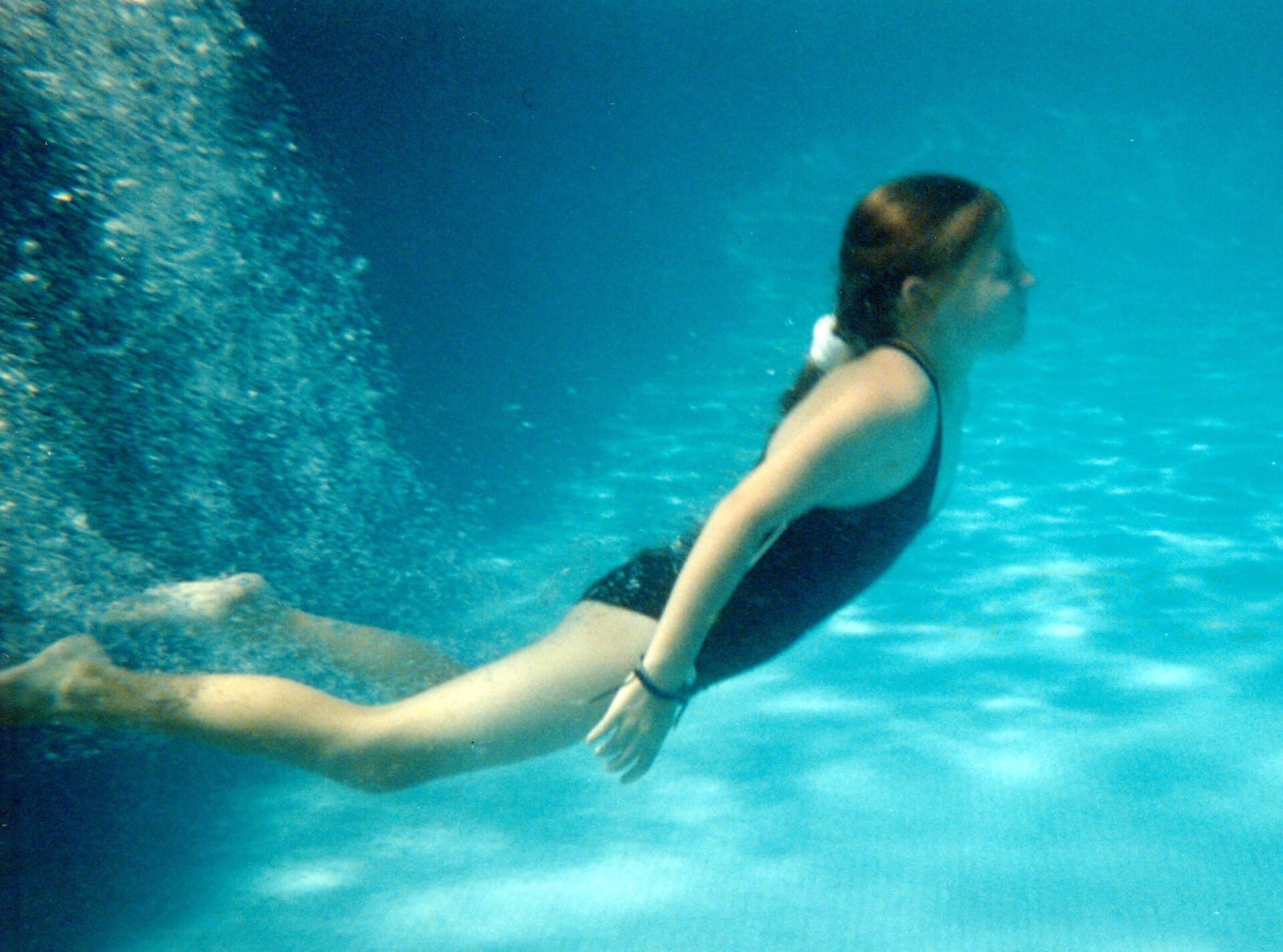 A girl swimming underwater in a blue pool