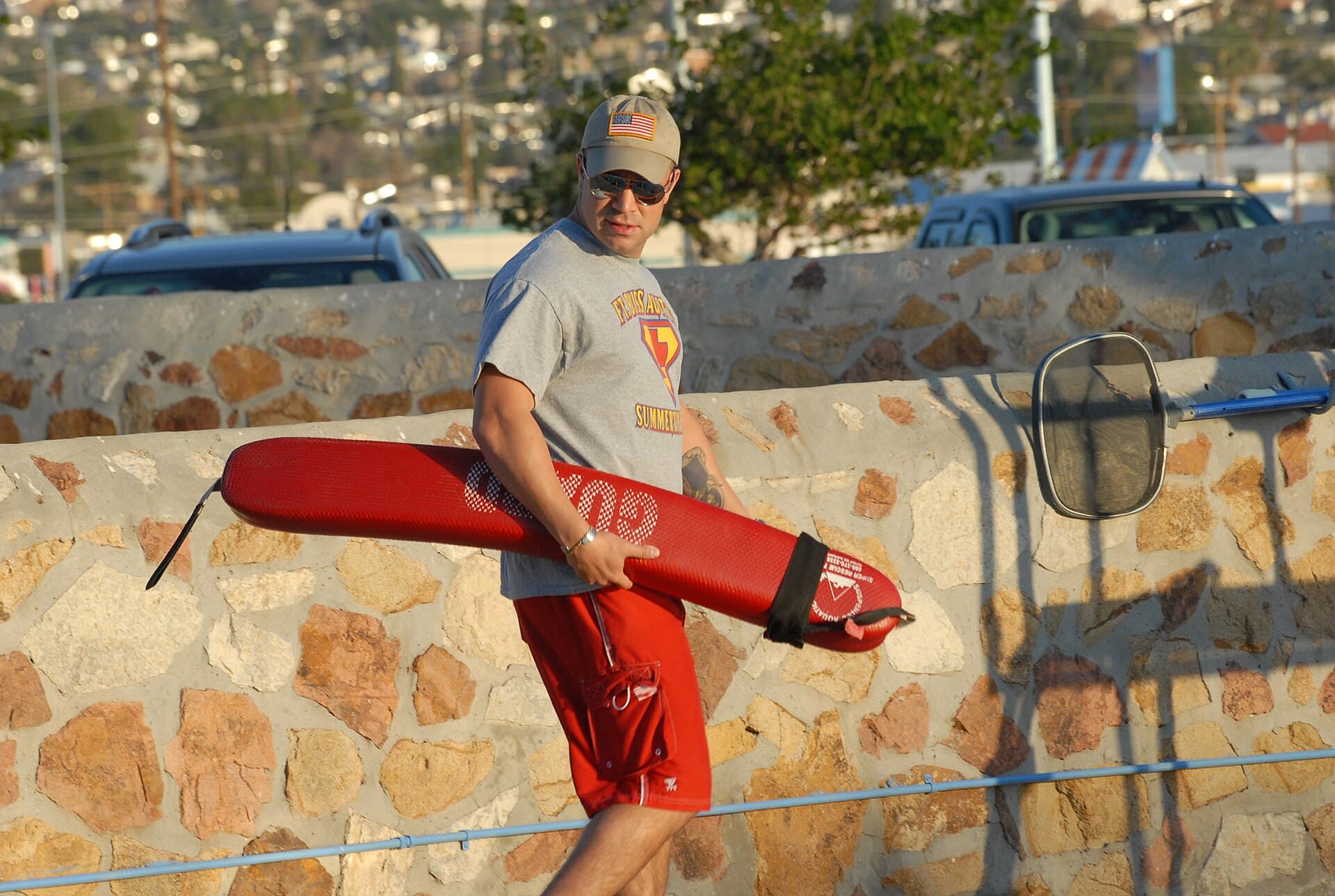 מציל אוחז מצוף הצלה אדום ליד בריכה